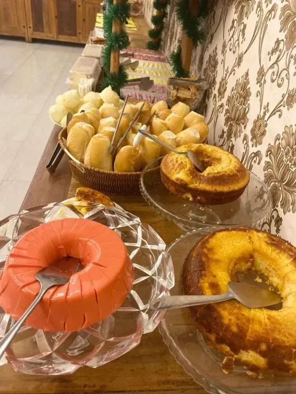 Buffet de café da manhã colonial com bolos caseiros, pudim, pães quentes e pão de queijo no Hotel Central Campo Grande